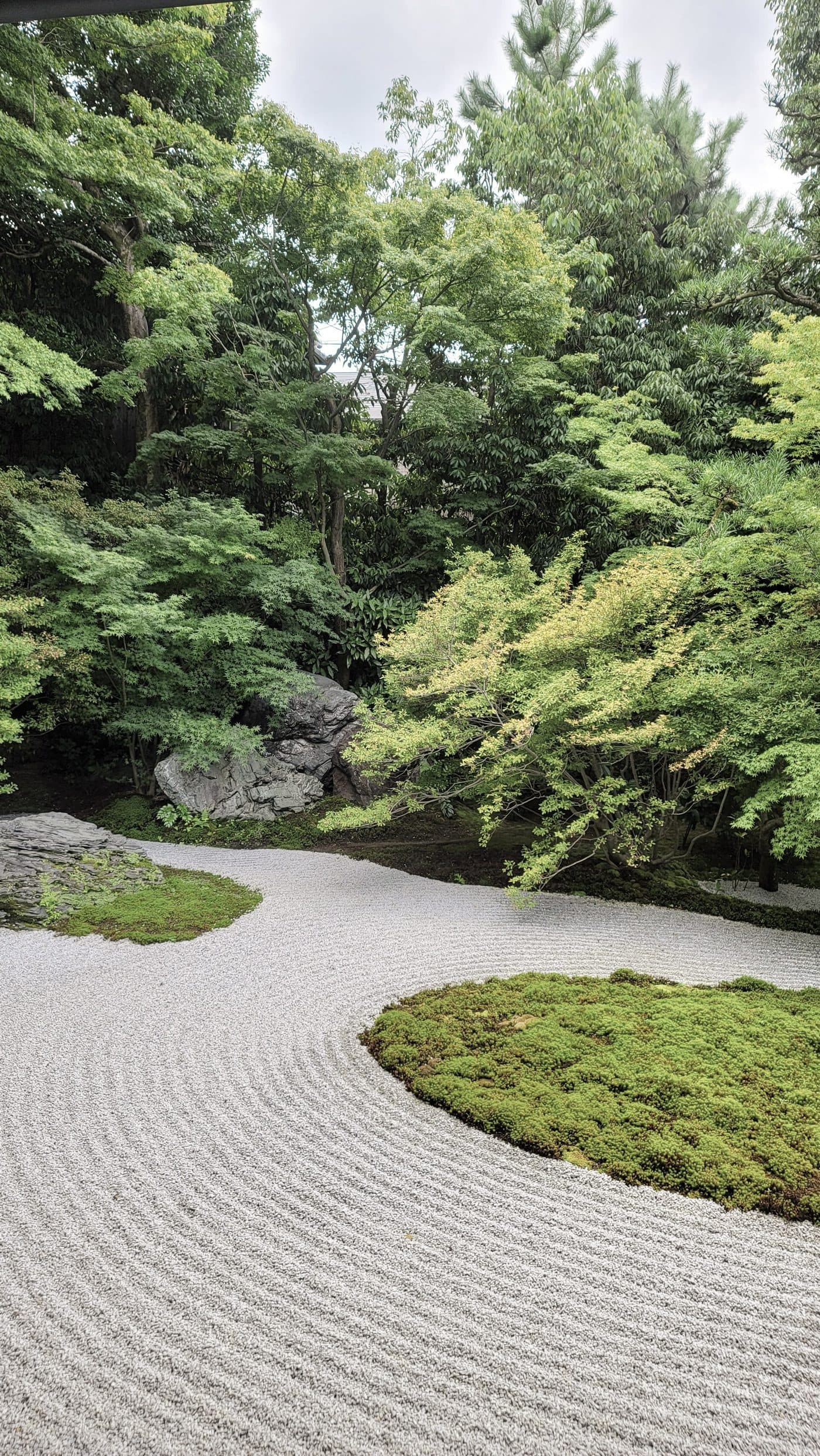 Grava rastrillada en ondas alrededor de una isla de musgo, en un jardín japonés